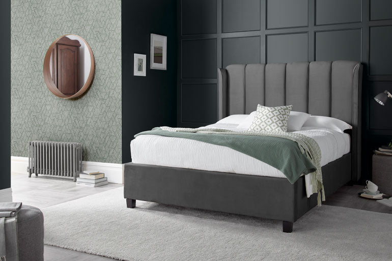 A double bed in grey fabric with vertical stitching and wings