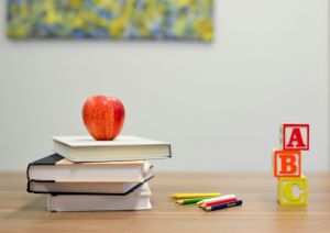 three books with an apple, pencils and alphabet blocks